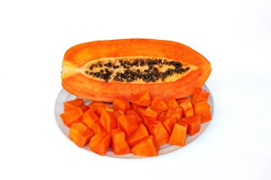 Dilimlenmiş ve yarıya bölünmüş olgun papaya, tabakta tohumlar, beyaz arka plan. Aşçılık, sağlıklı tarifler ve tropikal temalar için egzotik portakal meyvesi.