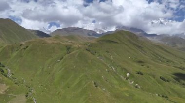 Bulutlu bir günde Gürcistan 'ın Svaneti bölgesinde Ushguli köyü yakınlarında yeşil çimlerle kaplı Kafkas Dağları..