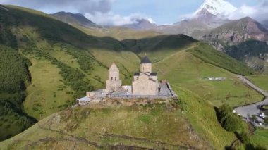 Kafkasya Dağları 'ndaki Gergeti Trinity Kilisesi' nin arka planda Kazbek Dağı ve Gürcistan 'ın Stepantsminda köyü yakınlarındaki görkemli karla kaplı zirveleri..