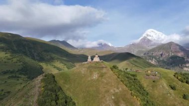 Kafkasya Dağları 'ndaki Gergeti Trinity Kilisesi' nin arka planda Kazbek Dağı ve Gürcistan 'ın Stepantsminda köyü yakınlarındaki görkemli karla kaplı zirveleri..