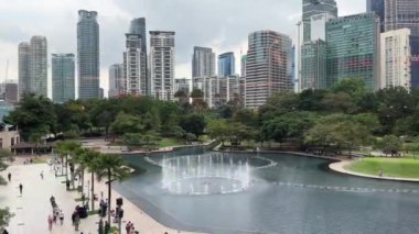 Kuala Lumpur, Malezya - 05.21.2024: Metropolitan şehir merkezi ve KLCC parkının gölü ve Petronas İkiz Kuleleri yakınlarındaki çeşmeleri panoramik manzarası.