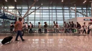 Kuala Lumpur, Malezya - 05.16.2024: Uluslararası Havaalanında yürüyen Hintli turistler. Terminale giden yolcular..