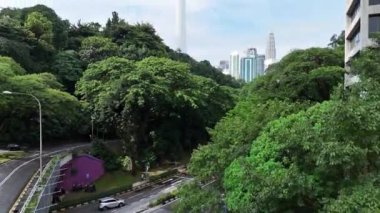 Kuala Lumpur, Malezya - 05.20.2024: Şehrin gökyüzü manzarası. Modern metropoldeki ağaçlar ve gökdelenlerin zıt kombinasyonu.