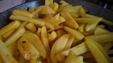 Hareketli bir mutfakta, altın patates çubukları ışıldayan bir tavada süzülürken cızırdar ve baştan çıkarıcı bir koku yayar. Patateslerin canlı renkleri mutfakla çok uyumlu.