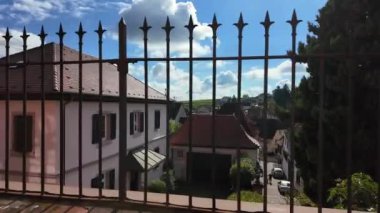 Resimli bir manzara, sıcak güneş ışığıyla yıkanmış antika bir kasabanın özünü yakalıyor. Yüksek bir bakış açısından, rahat evlerin çatıları ve çevreleyen yeşillikler uyumlu bir karışım oluşturur.