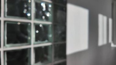 Bu büyüleyici an, gün boyunca camdan bir duvardan yansıyan ışığın etkileşimini yakalar. Temiz cam bloklar, güneş ışığının filtrelemesi ve dökmesi gibi ilgi çekici bir desen oluşturuyor.