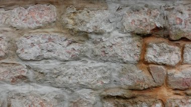 Bu desenli taş duvar, gri, bej ve turuncu ipuçlarının çeşitli tonlarında yıpranmış tuğlaların karışımını gösteriyor. Yüzey, zamanın düzensiz dokusunda ve ince renk değişimlerinde geçişini ortaya koyuyor. Bu da yaşını ve ele maruz kaldığını gösteriyor.