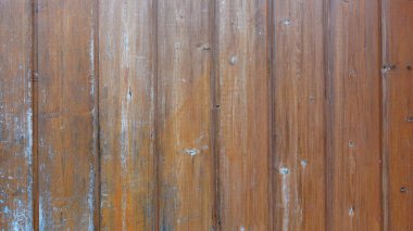 Ahşap duvarda sıcak ve davetkar bir doku sergileniyor. Bu da dikey kalasların doğal bir düzenini ortaya koyuyor. Her tahta kahverenginin zengin tonlarını sergiler, ince renk değişiklikleriyle birlikte karakter ekler.