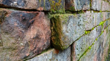 This close-up view reveals a weathered stone wall, adorned with patches of vibrant moss and lichen contributing to its rustic charm. The stones vary in shape and size, arranged in a haphazard yet harmonious manner, highlighting the craftsmanship of a clipart