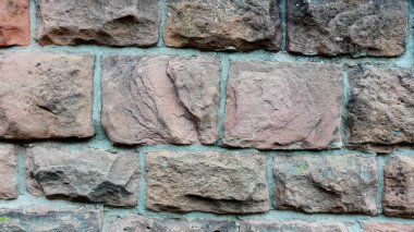 The sturdy wall consists of an arrangement of rough, weathered bricks in various shades of brown and gray. Each stone exhibits unique textures and patterns, showcasing the natural beauty and clipart