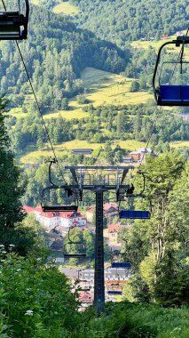 Polonya 'nın Pieniny Ulusal Parkı, Szczawnica' da yazın ağaçlar arasında dağa tırmanan fünikülerin dikey fotoğrafı. Aktif yaşam tarzı, yürüyüş, seyahat ve açık hava macera temaları için mükemmel.
