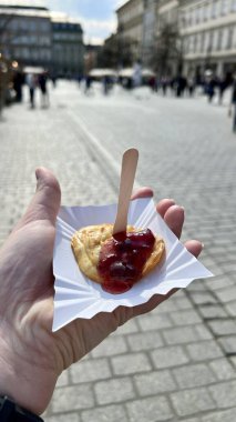 Sokak fuarında geleneksel Polonya oscypek peynirini reçelle tutan bir kadının dikey fotoğrafı. Gıda, kültür, seyahat ve yerel gelenek temaları için ideal.