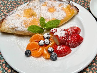Süzme peynirli, taze meyveyle süslenmiş ince krepler. Geleneksel Polonya mutfağı, ev yapımı yemekler ve taze malzemelerin ve mutfak geleneklerinin altını çizen tasarımlar için mükemmel bir tema..