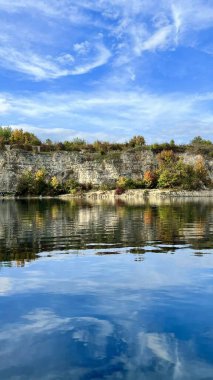 Vertical photo of Zalew Zakrzowek with rocks and sky reflected in blue water. Ideal for nature, travel, outdoor, and scenic landscape themes. Perfect for peaceful and serene visuals. clipart