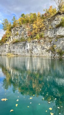 Vertical photo of Zalew Zakrzowek with rocks and sky reflected in blue water. Ideal for nature, travel, outdoor, and scenic landscape themes. Perfect for peaceful and serene visuals. clipart