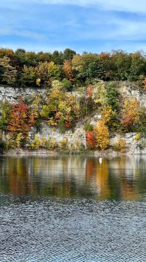 Vertical photo of Zalew Zakrzowek with rocks and sky reflected in blue water. Ideal for nature, travel, outdoor, and scenic landscape themes. Perfect for peaceful and serene visuals. clipart