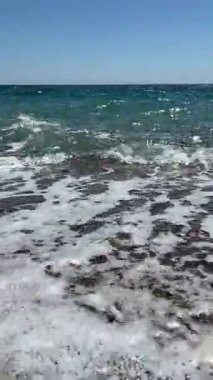Kıyıya doğru yaklaşan küçük bir deniz dalgasının dikey videosu. Okyanus, sahil, doğa, rahatlama ve kıyı temaları için ideal..