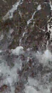 Baltık Denizi 'nin kumlu sahilde dalgalar halinde yuvarlanışını gösteren dikey bir video. Sakin deniz, sahil, doğa, okyanus, sükunet, deniz kenarı, rahatlama, sahil manzarası, huzurlu dalgalar..