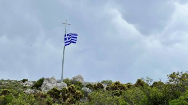 Dramatik gökyüzüne, Kastellorizo adasına, Yunanistan 'a, ulusal sembole, Akdeniz atmosferine, seyahat beldesine, vatanseverlik sahnesine, turizme, kültüre, kopyalama alanına karşı rüzgarda dalgalanan Yunan bayrağı 