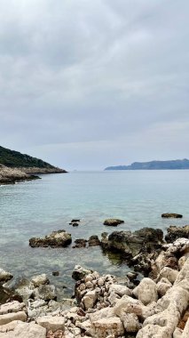 Türkiye 'nin Choban Beach kentindeki turkuaz su ve yeşil tepelerle kayalık kıyıların dikey fotoğrafı. Akdeniz doğası, Lycian Yolu, kıyı manzarası, seyahat, yaz tatili, huzurlu sahil kaçışı