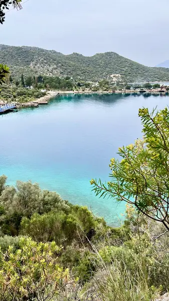 Türkiye 'de mavi bir göl ve dağlarla çevrili Akdeniz manzarasının dikey fotoğrafı. Sahil seyahati, yaz tatili, huzurlu doğa, sahil gezisi, rahatlatıcı kaçış, manzaralı manzara.. 