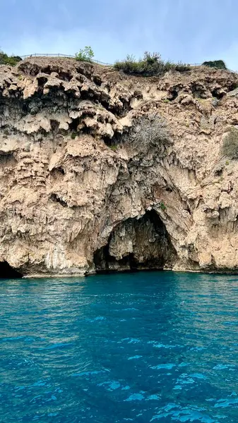 Turkuaz denizin kayalık uçurum manzaralı dikey fotoğrafı. Yaz tatili, Akdeniz, seyahat, kıyı manzarası, doğa, Antalya ili, Türkiye, açık hava manzarası, huzurlu yaz günü. 