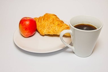 The image shows a breakfast setting with a croissant, a red apple, and a cup of black coffee on a white plate. The croissant is golden brown and flaky, the apple is shiny and red, and the coffee is dark and steaming.  clipart