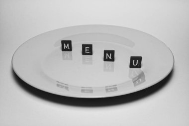 Üzerinde dört siyah karo olan beyaz bir plaka. Her birinde bir harf var. Harflerde 