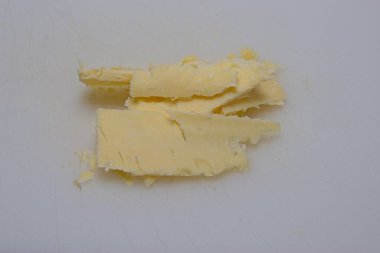 Beyaz bir yüzeyde birkaç ince peynir dilimi. Peynir biraz dengesiz kesilmiş gibi görünüyor, bazı parçalar üst üste biniyor..