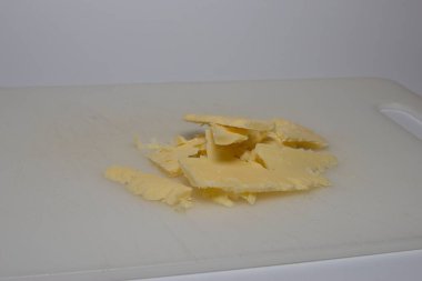 Beyaz bir yüzeyde birkaç ince peynir dilimi. Peynir biraz dengesiz kesilmiş gibi görünüyor, bazı parçalar üst üste biniyor..