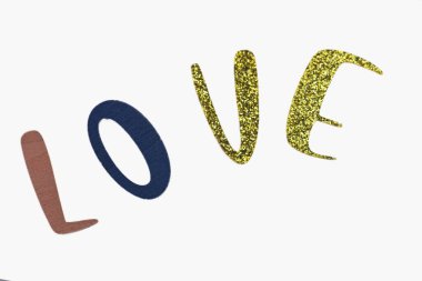 'LOVE' spelled out in colorful, textured letters on a light background. The 'L' is pink, the 'O' is blue, and the 'V' and 'E' are gold glitter, creating a playful and cheerful message.