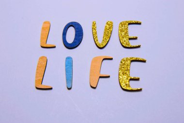 Açık mor arkaplanda renkli, desenli harflerle 