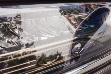 Modern arabaların ayrıntılı yakın çekim farı montajı, ksenon ampulü sergilenmesi, karmaşık yansıtıcı ve temiz lens. Otomotiv tasarımını vurgulayan yüksek çözünürlüklü resim.
