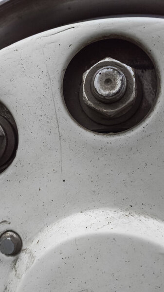 A close-up view of several metal nuts and bolts securing a section of a white vehicle part.