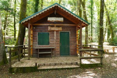 Dikey tahtalardan yapılmış bir ev. Ön kapı kapalı, pencere kepenklerle kapalı, bitmemiş teras var. Evin yanında bir masa ve basit dinlenme aşıkları için bir bank var..