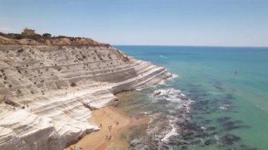 Sicilya sahilindeki Türk Merdivenleri. İnsansız hava aracı teraslı çıkıntılarını gösterir. Turistler kar beyazı çıkıntıları boyunca yürürler. Kayanın beyazlığıyla denizin gölgeleri arasındaki zıtlık..