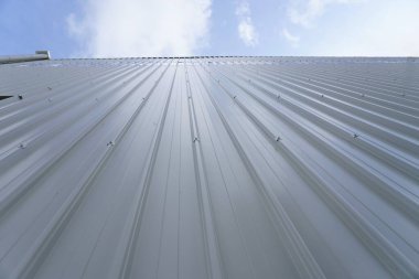 Dikey beyaz metal sandviç panellerinden yapılmış bir duvar. Duvarlar yukarı doğru uzanıyor gibi görünüyor, yükseklik ve boşluk hissini arttırıyor. Bu endüstriyel mimarinin bir unsurudur..