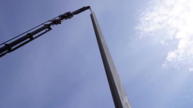 Güçlü bir kamyon vinci metal bir direği kaldırır..