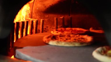 Fırının ortasında dönen bir taşın üzerinde pizza.