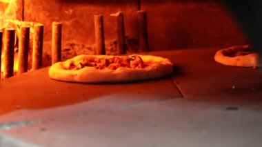 Fırının ortasında dönen bir taşın üzerinde pizza.