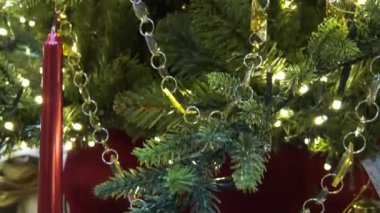 Güzel dekore edilmiş bir Noel ağacı. Ağacın yanıp sönen ışıkları sıcak bir parıltı yayarak rahat ve büyülü bir tatil atmosferi yaratıyor. Yakın plan çekimde dokular ve detaylar vurgulanır.