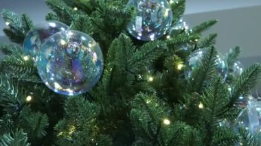 Güzel dekore edilmiş bir Noel ağacı. Ağacın yanıp sönen ışıkları sıcak bir parıltı yayarak rahat ve büyülü bir tatil atmosferi yaratıyor. Yakın plan çekimde dokular ve detaylar vurgulanır.