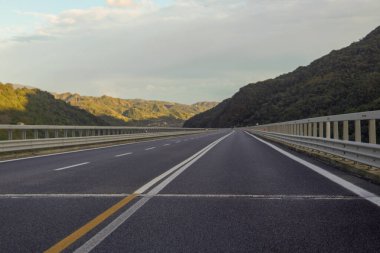 Dağların arasından geçen ve dağ zirvelerinin muhteşem manzarasını sunan bir otoyol..