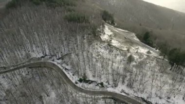 Karlı bir dağ yolunda uçan bir dron. İnsansız hava aracının hava görüntüsü çarpıcı bir dağ yolunu yakaladı dramatik bir kar manzarası boyunca ilerliyordu..