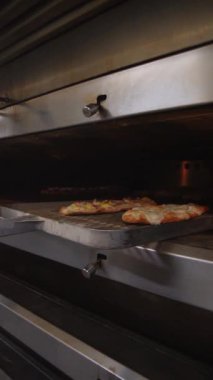 Baker taze pişmiş ekmeği fırından çıkarır. Sıcak somunlar, geleneksel pişirme süreci. Küçük fırın ayarları.