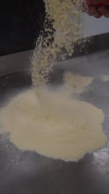 Profesyonel bir fırında hamur şekillendirmeye hazırlanıyor. Bir fırıncı paslanmaz çelik bir masaya mısır unu serper, yüzeyi pişirmeye hazırlar..