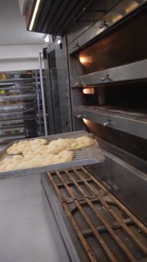 Baker taze pişmiş ekmeği fırından çıkarır. Sıcak somunlar, geleneksel pişirme süreci. Küçük fırın ayarları.