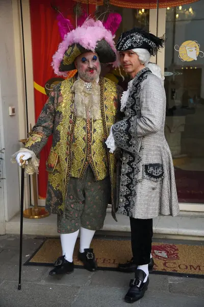 Geleneksel Venedik karnaval kostümlü insanlar Venedik Karnavalı sırasında tarihi bir avluda fotoğraf için poz veriyorlar. Venedik, İtalya 02: 16. 2025