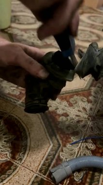 Bir çamaşır makinesi tamircisi bozuk para ve anahtarları çıkarmak için bir drenaj hortumu keser. Alet Tamiri, Kayıp Mal Kurtarma, Bakım