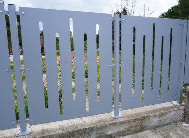 Dikey kesikli modern metal çitler. Dekoratif lazer kesimli, sağlam beton bir zemine monte edilmiş oval çitler. Kentsel mimari için modern minimalist tasarım, özel evler